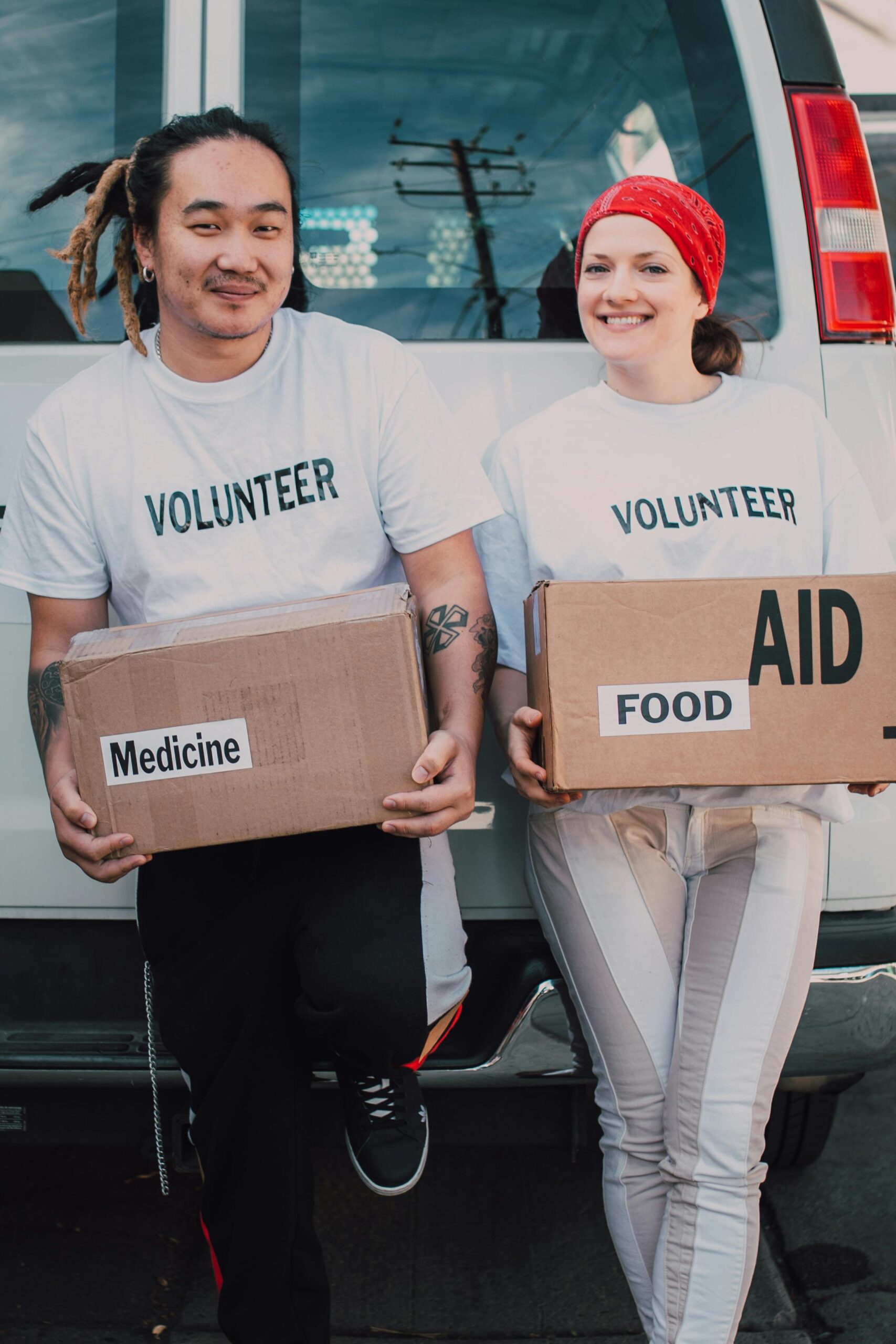Two volunteers holding aid boxes, supporting charitable work and reviews