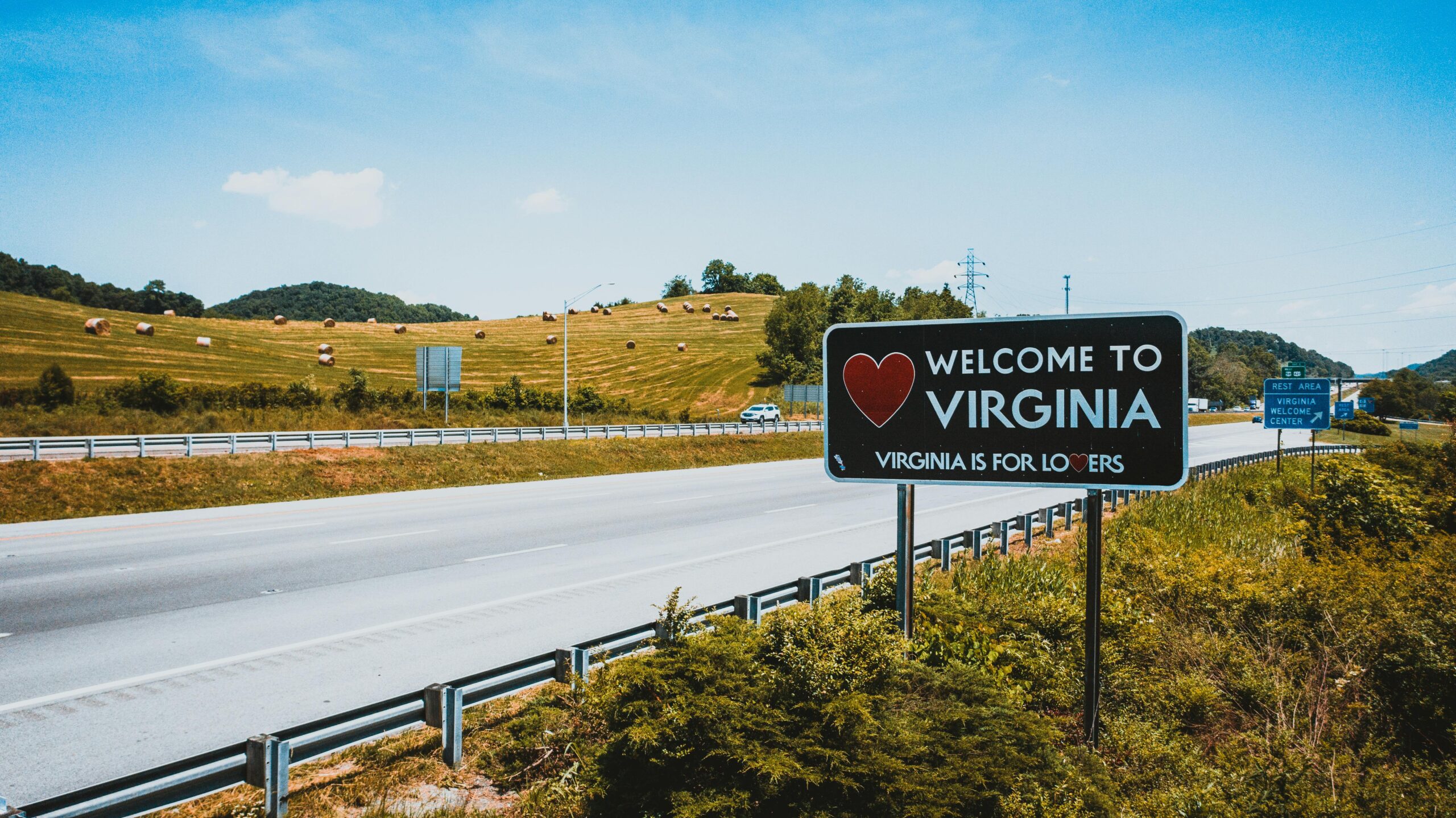 Welcome to Virginia sign on a sunny highway, inviting travelers in a picturesque rural setting.